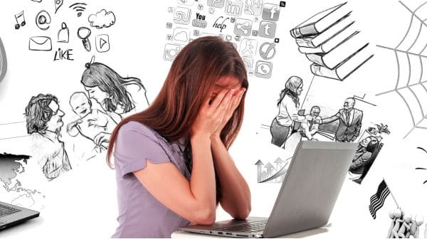 Uma pessoa em frente ao computador com as mãos no rosto e vários pensamentos confusos ilustrados ao fundo