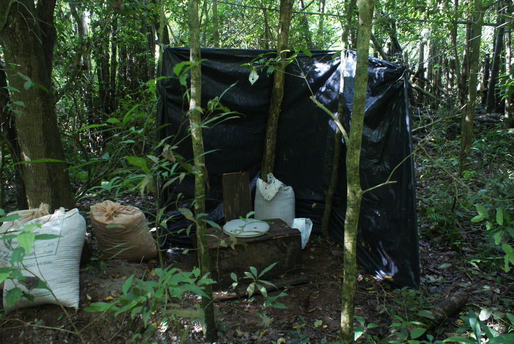 banheiro improvisado do acampamento com lona e sacos de serragem